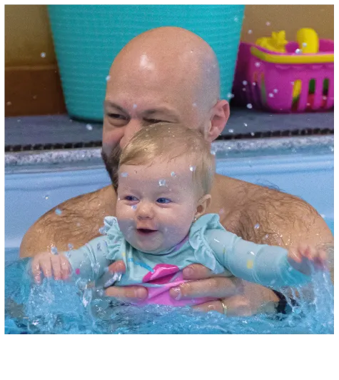 Pai segurando a filha a no colo dentro da piscina